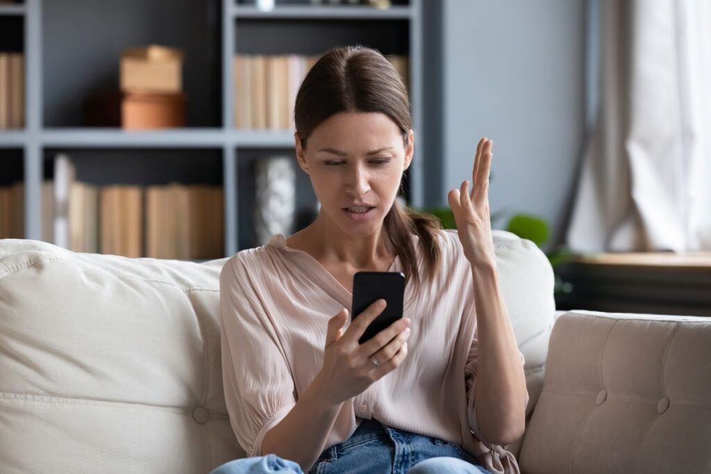 Femme frustrée regardant son téléphone, ayant des difficultés avec la réception d'emails.